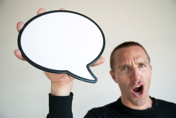 Enthusiastic man with short hair shouting a message while holding a blank speech bubble