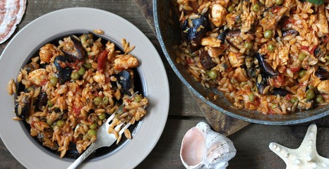 orzo pasta with mussels, seashells and chicken. Seafood paella, traditional spanish dish. Paella on rustic black wooden table. Top view