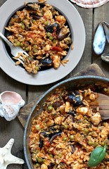 orzo pasta with mussels, seashells and chicken. Seafood paella, traditional spanish dish. Paella on rustic black wooden table. Top view