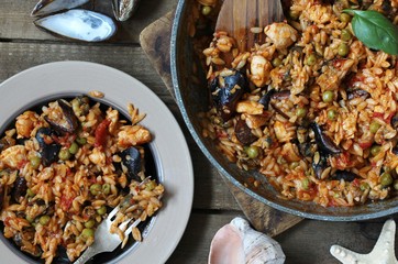 orzo pasta with mussels, seashells and chicken. Seafood paella, traditional spanish dish. Paella on rustic black wooden table. Top view