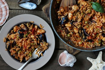 orzo pasta with mussels, seashells and chicken. Seafood paella, traditional spanish dish. Paella on rustic black wooden table. Top view