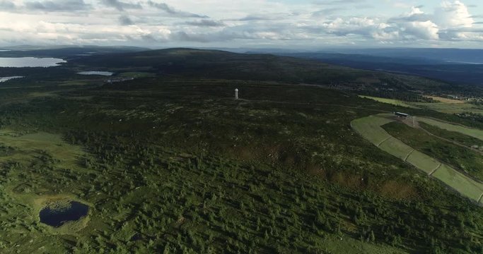 Spectacular aerial view of forest and lakes on flat pane of oyer. Drone fles towards meteorological tower.