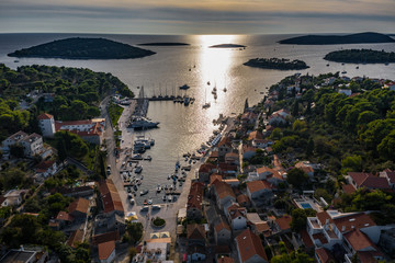 Croatia, Maslinica, 15 September 2019: Drone view point on moored in an equal row sailboats at sunset, participant of a sailing regatta, people have a rest after racing day, azure water, pier