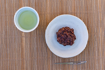 sticky rice cake coated in smashed sweet beans on a pottery tray.