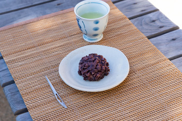 sticky rice cake coated in smashed sweet beans on a pottery tray.