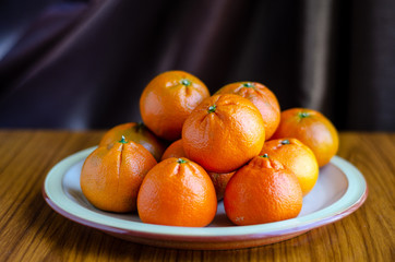 Mandarin oranges piled up on a plate.