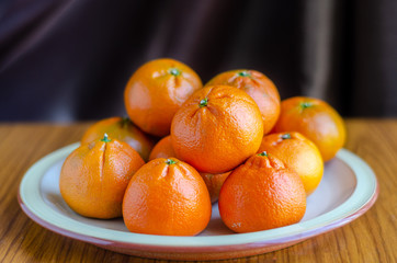 Mandarin oranges piled up on a plate.