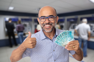 Homem de 50 anos sorridente mostrando dinheiro