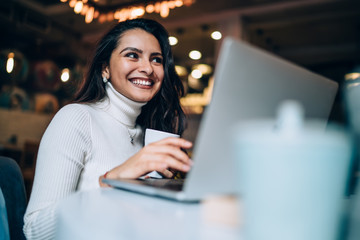 Happy lady working with laptop in cafe