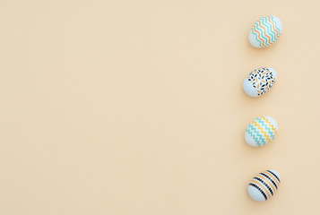 Decorated Easter eggs lie on the yellow background. Happy Easter holiday and minimalism concept. Greeting, invitation card. Flat lay style with copy space.