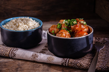 Cooking at home. Homemade meatballs and boiled rice in ceramic bowls, on a kitchen napkin. Fork and ceramic dishes.