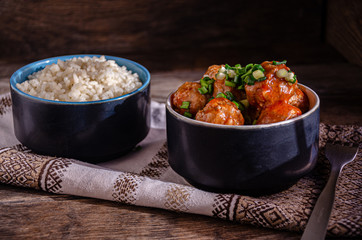 Cooking at home. Homemade meatballs and boiled rice in ceramic bowls, on a kitchen napkin. Fork and ceramic dishes.