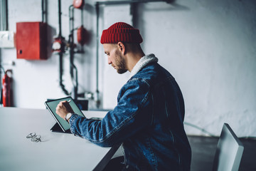 Concentrated freelancer drawing on tablet in loft