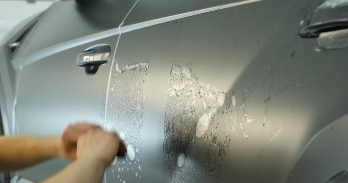 Close up of paint protection film installation on modern luxury car. PPF is polyurethane film that wrap car paint to protect paint surface from stone chips, bug splatter, and abrasion.