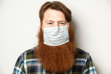 A man with a red hair and a red beard wearing a face mask.  A bearded man with a face mask...