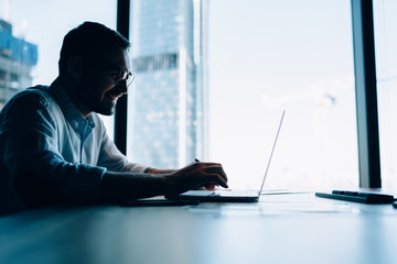 Cheerful man typing on laptop in office © BullRun
