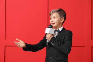 Little journalist with microphone on color background