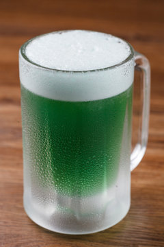 Cerveja verde de saint Patrick em caneca gelada sobre mesa de madeira