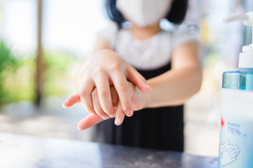 Coronavirus Covid-19 concept.Little asian chinese girl wearing mask for protect coronavirus and clean hand alcohol gel sanitizer pump before come to super market store for stop corona virus outbreak.