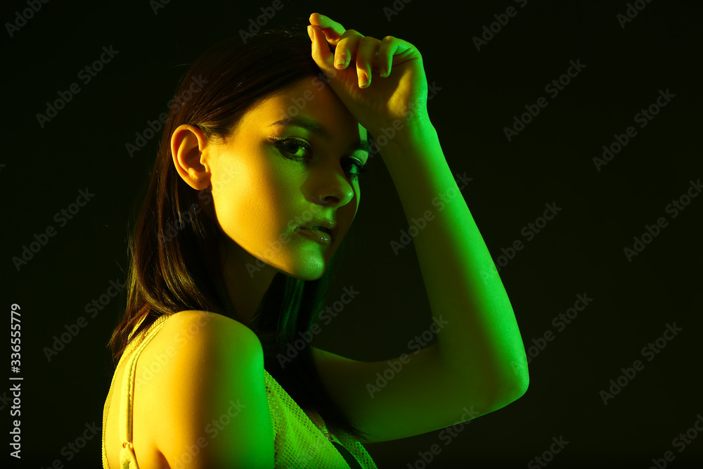 Wall mural Toned portrait of beautiful young woman on dark background