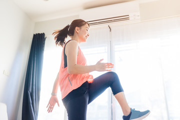 Video streaming Stay home.home fitness workout class live streaming online.Asian woman doing strength training cardio aerobic dance exercises watching videos in the living room at home.Covid-19.