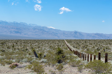 Fototapeta na wymiar Thick wooden railroad tie beams and steel cable combined into Vehicle Barrier Fencing along the boundary of Tule Springs Fossil Beds National Monument outside Las Vegas, NV, USA