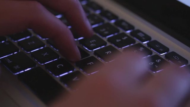 Hands of a man typing on a keyboard of a laptop.