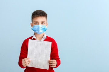 Pupil in protective mask and with answer sheet for school test on color background. Concept of epidemic