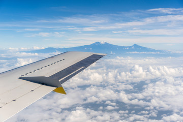 Obraz premium View from the airplane window of the Kilimanjaro volcano in the white clouds in Tanzania, Africa