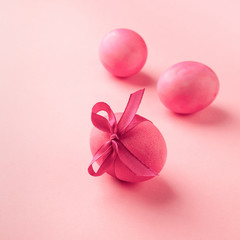 Bright pink eggs with satin bow on a pink background. Festive spring concept. Color trend. Selective focus close-up.