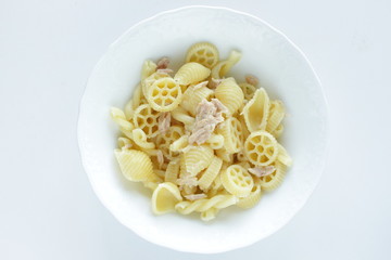 Prepared pasta and tuna salad in white bowl on white background