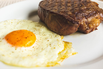 fried egg and steak on white plate
