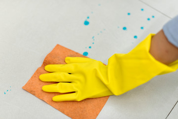 Woman wearing yellow rubber gloves and cleaning the surface