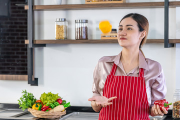 A beautiful woman is throwing bell pepper, sweet pepper or capsicum in the kitchen.