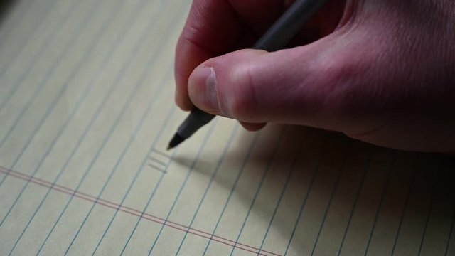 Caucasian hand using a pen to draw tally marks for counting