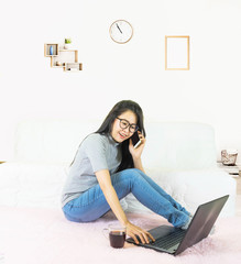 Young beautiful asian woman wore gray t shirt and jean, lying on pink carpet in living room ,work online lifestyle,relax at home with coffee mug,home working laptop,work from home