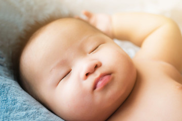 top view Portrait of a newborn Asian cute baby boy wore blue Infant bodysuit on the bed , Charming Fat baby 5 month old lies in bed with a doll,enjoy and happy
