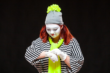 Portrait of female mime artist, isolated on black background. Young woman in striped clothes and...