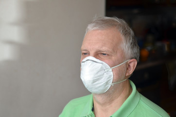 Elderly man wearing  a disposable respirator for infection protection
