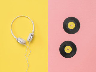 White headphones and yellow vinyl discs on a pink and yellow background.