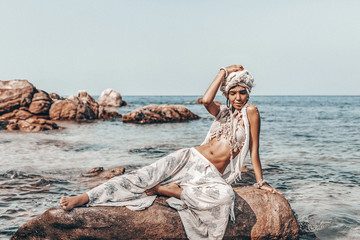 cheerful young stylish woman wearing turban on the beach