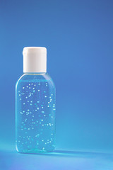 Obraz na płótnie Canvas A bottle of hand sanitizer gel. Hand hygiene as coronavirus protection. Antivirus and antibacterial product. Blue liquid with white round granules. Copy space for text
