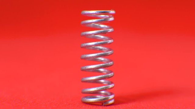 Standing a small metal spring on red paper - close up
