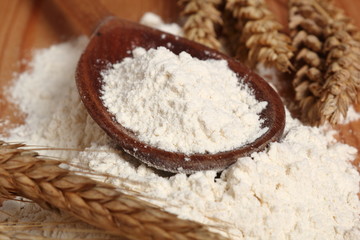 Wooden spoon with flour and wheat ears