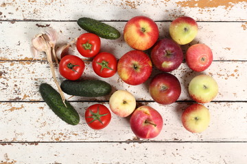 Tomatoes, Cucumbers, Potatoes, Garlic and Apples on peeled paint plank background. Directly Above.