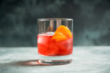 Red traditional old fashioned cocktail with orange zest on the rustic background. Selective focus. Shallow depth of field.
