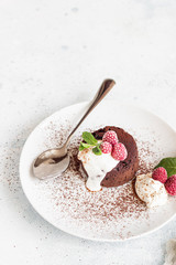 Delicious chocolate fondant or lava cake with cream, raspberries and cream, light grey concrete...