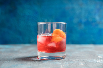 Red traditional old fashioned cocktail with orange zest on the rustic background. Selective focus. Shallow depth of field.