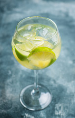 Rum based cocktail with lime in wine glass (variation of cuba libre) on the rustic background. Selective focus. Shallow depth of field.