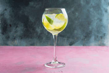 Rum based cocktail with lime in wine glass (variation of cuba libre) on the rustic background. Selective focus. Shallow depth of field.